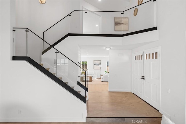 entryway featuring stairway, a towering ceiling, baseboards, and wood finished floors