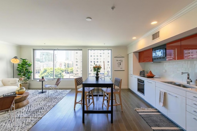 dining area featuring ornamental molding, dark wood-style flooring, and baseboards