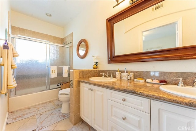 full bathroom featuring double vanity, visible vents, bath / shower combo with glass door, and a sink