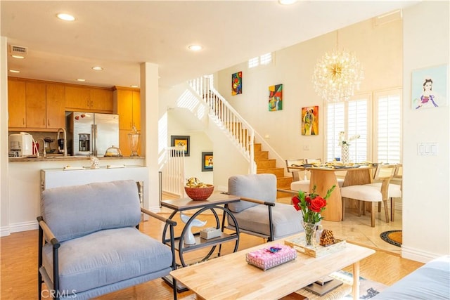 living room featuring visible vents, stairs, light wood-type flooring, a notable chandelier, and recessed lighting