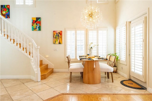 dining area with stairs, a high ceiling, a notable chandelier, and baseboards