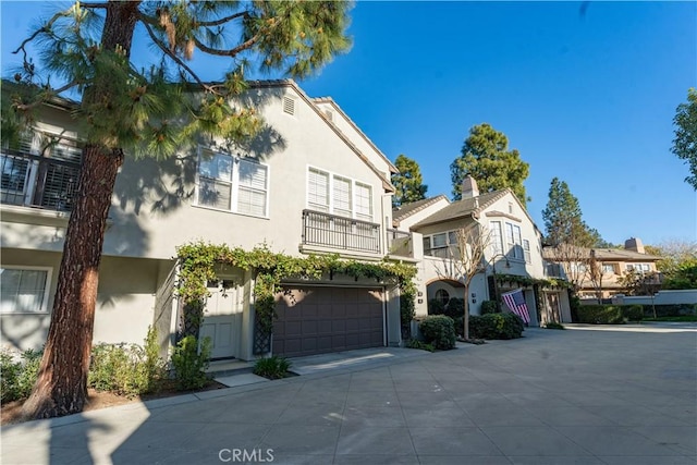 view of property with a garage, concrete driveway, and stucco siding