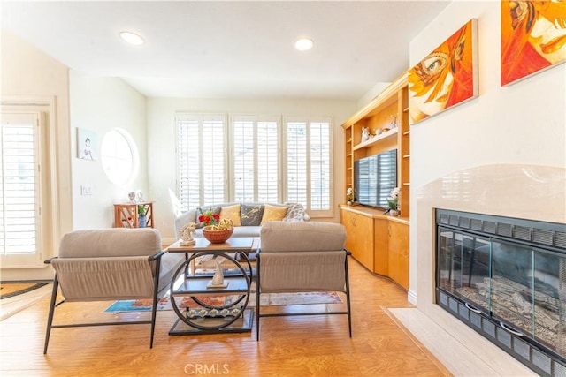 living room featuring light wood finished floors, a high end fireplace, and recessed lighting