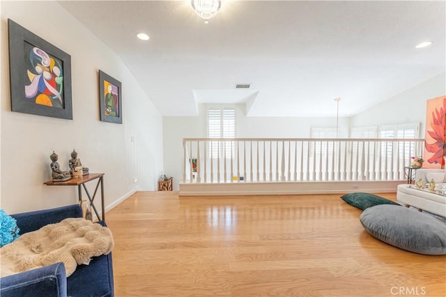 living area with vaulted ceiling, plenty of natural light, wood finished floors, and visible vents