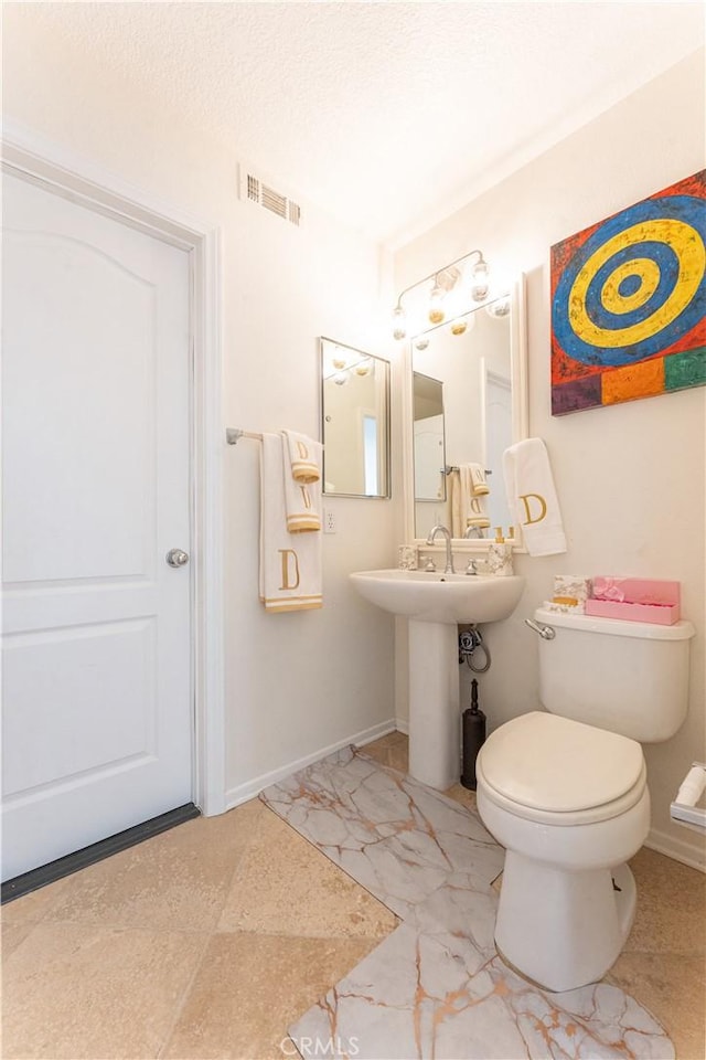 bathroom featuring toilet, baseboards, visible vents, and a sink