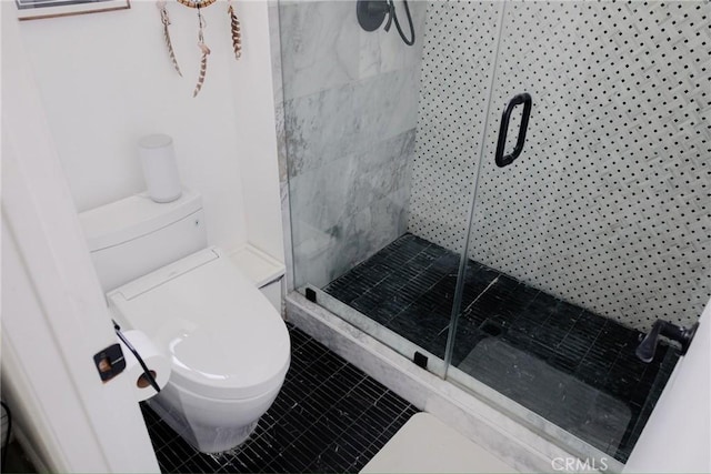 bathroom featuring tile patterned flooring, a shower stall, and toilet