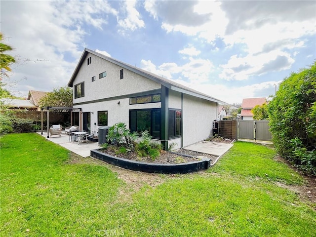 back of property featuring fence, a yard, a gate, stucco siding, and a patio area