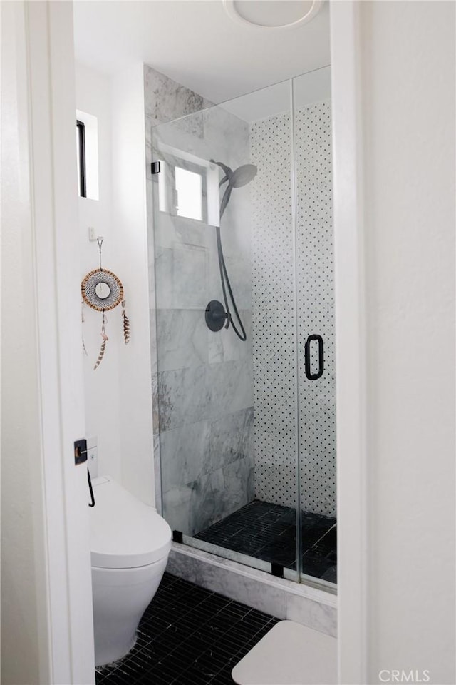 bathroom with a shower stall, toilet, and tile patterned floors