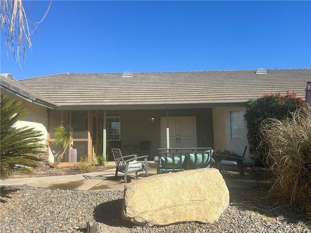 back of house featuring a patio area, a tiled roof, and stucco siding