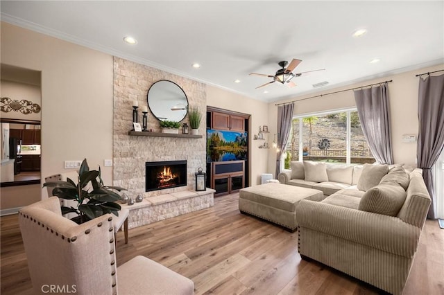 living area featuring a fireplace, recessed lighting, ornamental molding, ceiling fan, and light wood-type flooring