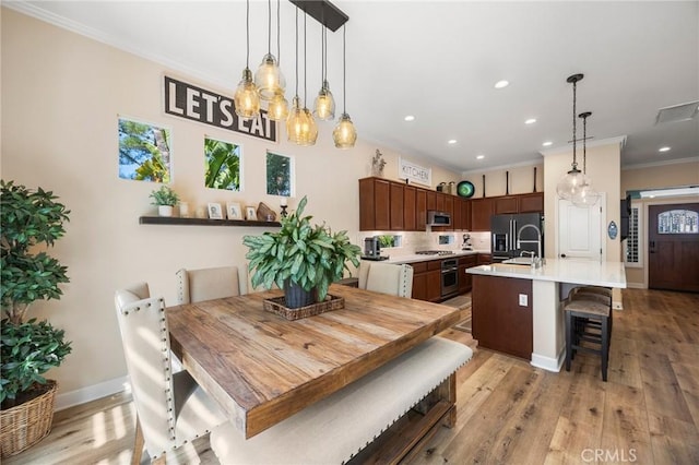 dining area with baseboards, recessed lighting, light wood-type flooring, and crown molding