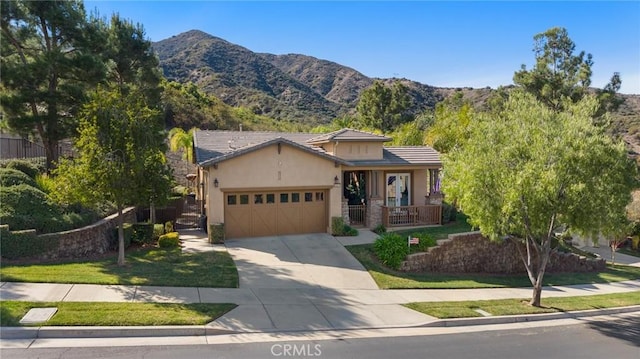 view of front facade featuring an attached garage, a mountain view, concrete driveway, a tiled roof, and stucco siding