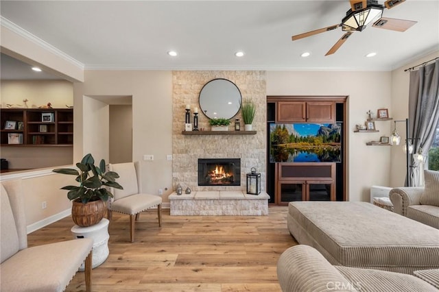 living room with light wood-type flooring, a fireplace, crown molding, and recessed lighting