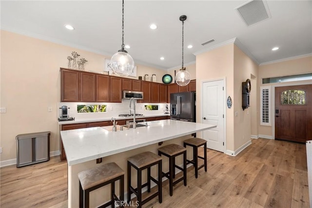 kitchen featuring visible vents, light countertops, black fridge, stainless steel microwave, and a center island with sink