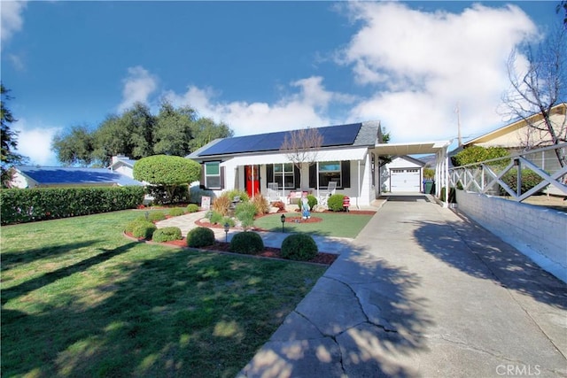 view of front of house featuring a porch, concrete driveway, a front yard, roof mounted solar panels, and a carport