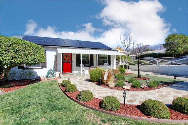 view of front of home with roof mounted solar panels and a front yard