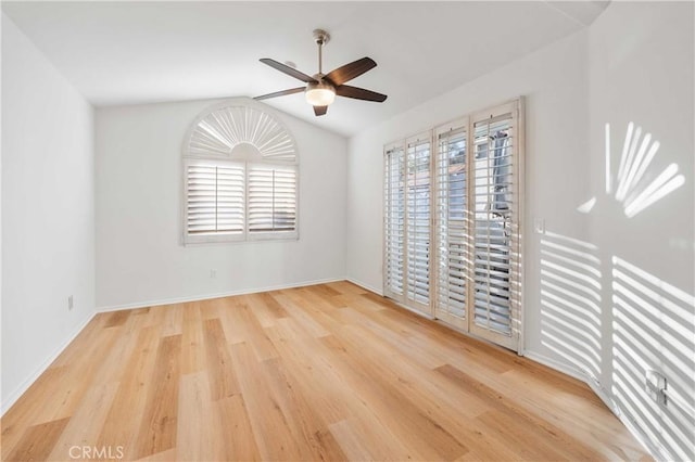 spare room with a ceiling fan, baseboards, vaulted ceiling, and light wood finished floors