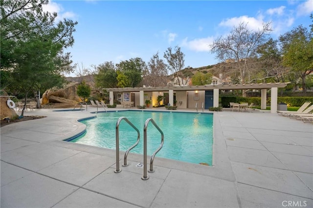 community pool with a patio area, a mountain view, and a pergola