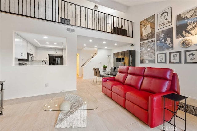 living area featuring baseboards, a high ceiling, visible vents, and recessed lighting