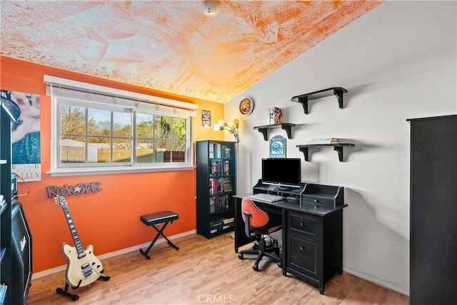 office area featuring lofted ceiling, baseboards, and light wood finished floors