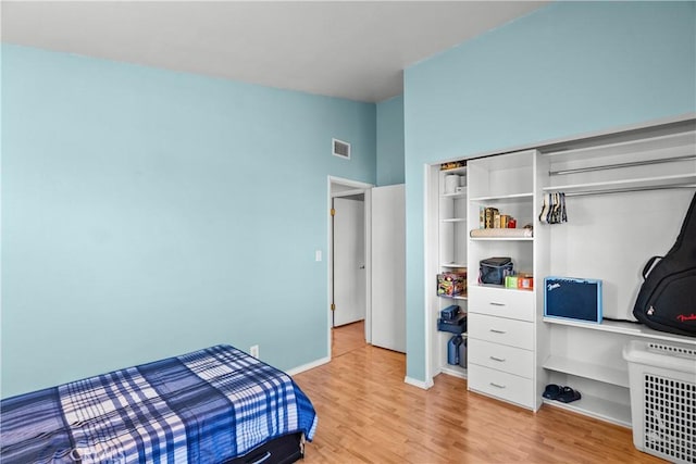 bedroom featuring lofted ceiling, light wood-style flooring, visible vents, and baseboards