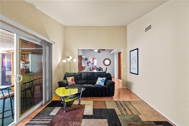 living area featuring light wood finished floors, a ceiling fan, visible vents, and baseboards