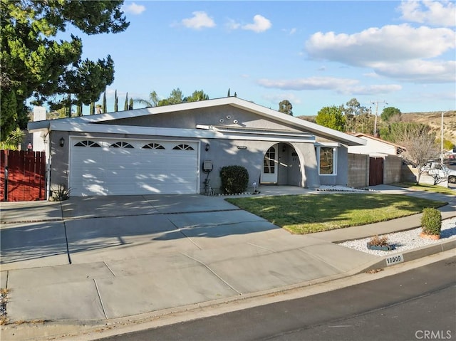 ranch-style home featuring stucco siding, concrete driveway, a front yard, fence, and a garage