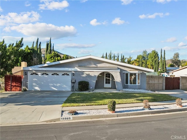 ranch-style house with an attached garage, fence, driveway, stucco siding, and a front lawn