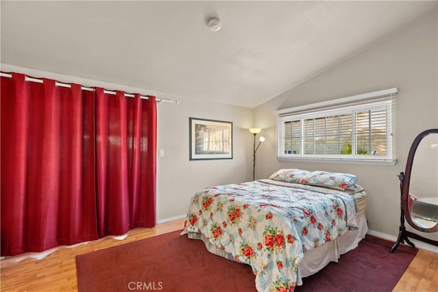 bedroom with lofted ceiling, baseboards, and wood finished floors