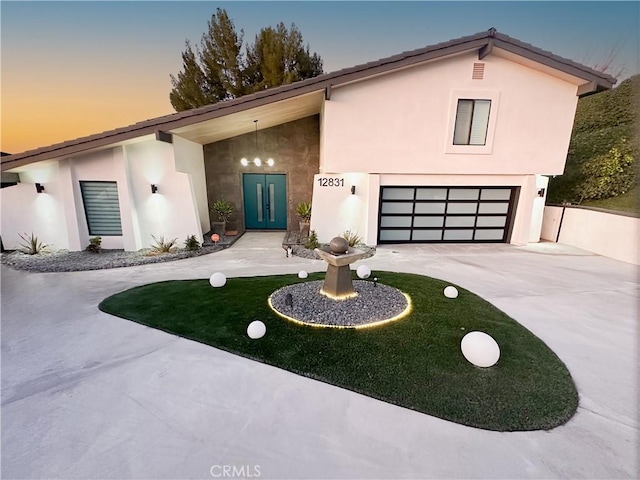 view of front of property with a garage, driveway, and stucco siding