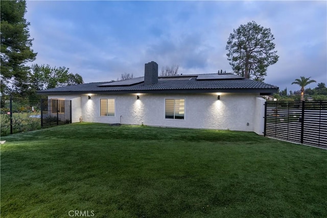 back of house with fence, a yard, a chimney, and stucco siding