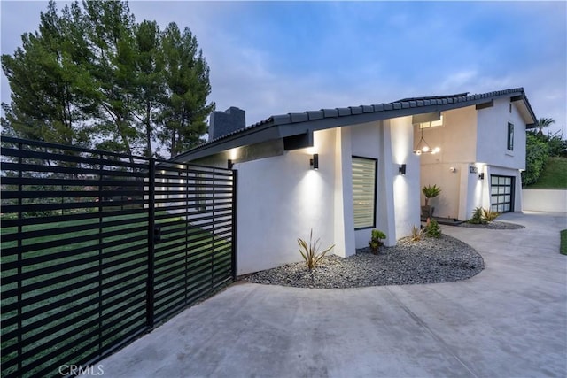 view of home's exterior featuring fence, a chimney, and stucco siding