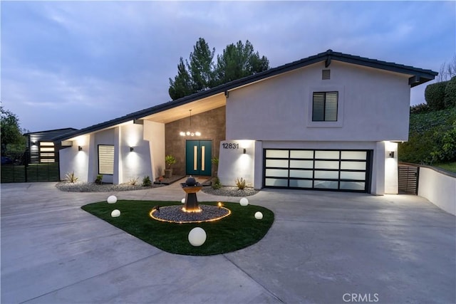 modern home featuring a garage, concrete driveway, fence, and stucco siding