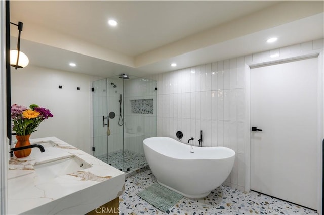 full bathroom with a soaking tub, a sink, a shower stall, tile walls, and recessed lighting