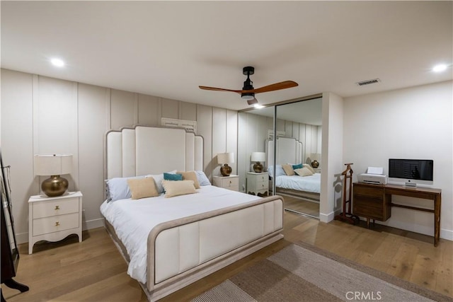 bedroom featuring light wood finished floors, ceiling fan, visible vents, and a closet