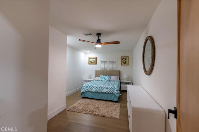 bedroom with baseboards, visible vents, ceiling fan, and wood finished floors