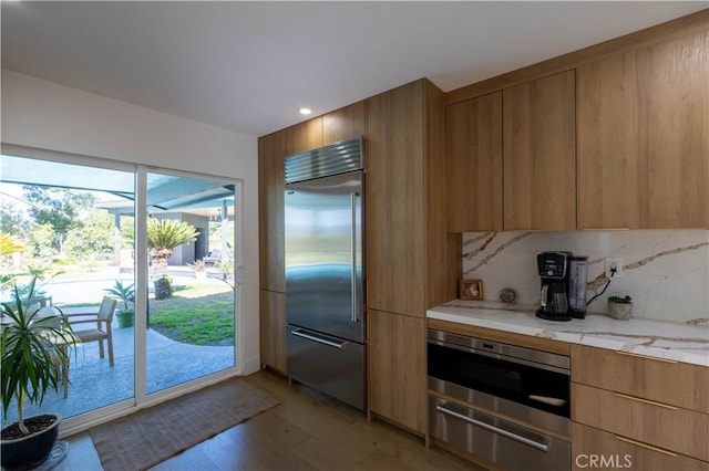 kitchen with a warming drawer, modern cabinets, decorative backsplash, and stainless steel built in fridge