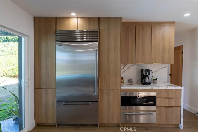 kitchen with a warming drawer, stainless steel appliances, modern cabinets, and backsplash