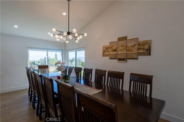 dining space featuring a chandelier, high vaulted ceiling, recessed lighting, wood finished floors, and baseboards