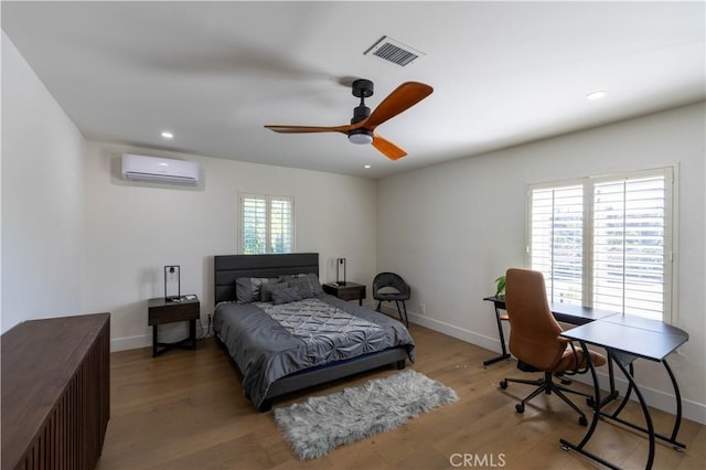 bedroom featuring baseboards, visible vents, wood finished floors, a wall mounted air conditioner, and recessed lighting