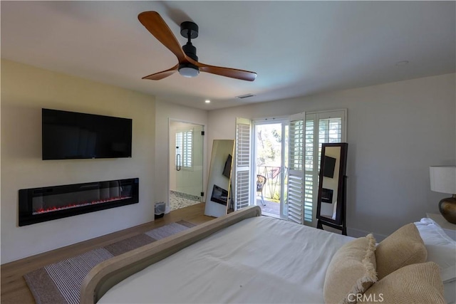 bedroom with visible vents, a ceiling fan, a glass covered fireplace, wood finished floors, and recessed lighting