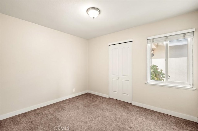 unfurnished bedroom featuring carpet floors, a closet, and baseboards