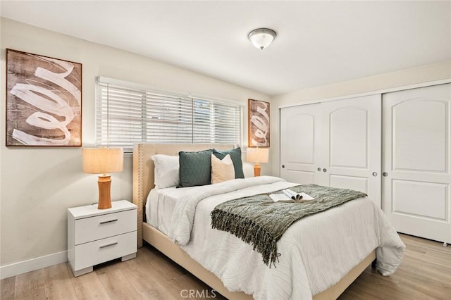 bedroom with light wood-type flooring, a closet, and baseboards