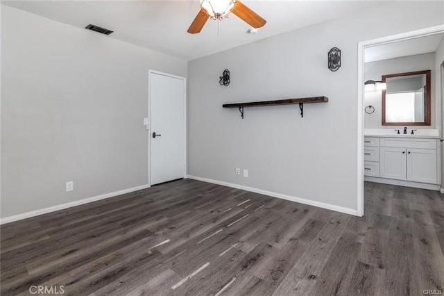 unfurnished room with dark wood-style flooring, a sink, visible vents, and baseboards