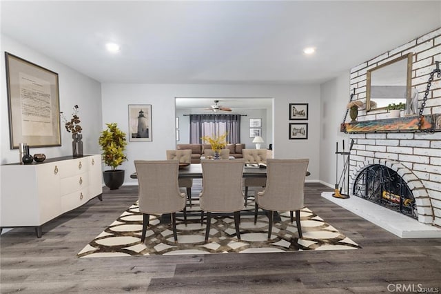 dining room with dark wood-style flooring, a fireplace, recessed lighting, ceiling fan, and baseboards