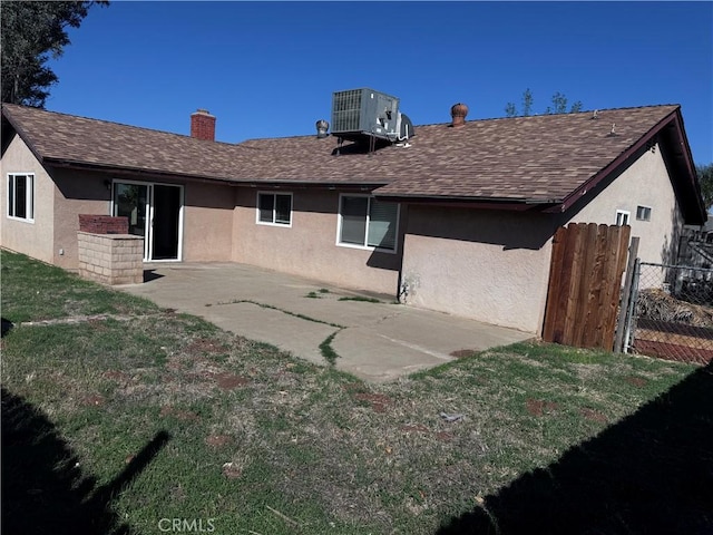 rear view of property with a shingled roof, cooling unit, and stucco siding