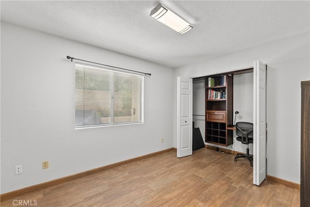 home office with a textured ceiling, baseboards, and wood finished floors