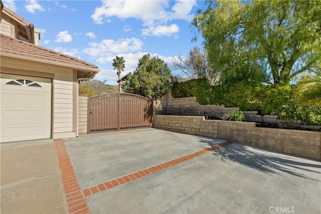 view of patio featuring a garage and a gate