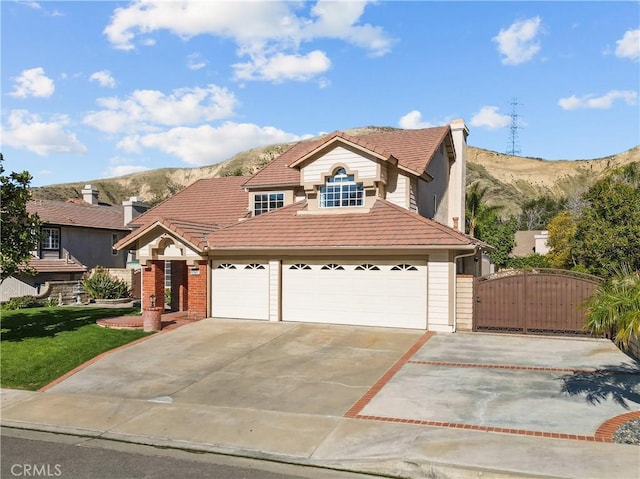 view of front of home with a garage, concrete driveway, a tiled roof, a gate, and a mountain view