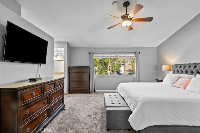 bedroom with a ceiling fan, light carpet, vaulted ceiling, and baseboards